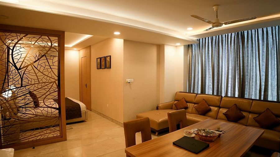 A spacious living room with a sectional sofa and decorative partition leading to another room - TGI Insignia, Bhopal