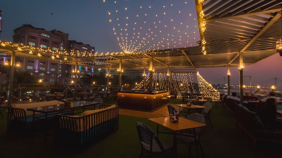 the outside deck with seating arrangements and fairy lights turned on during night time