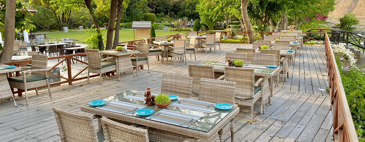 An image of outdoor seating area with wooden chairs and table surrounded by plants and trees - The Riverview Retreat, Corbett