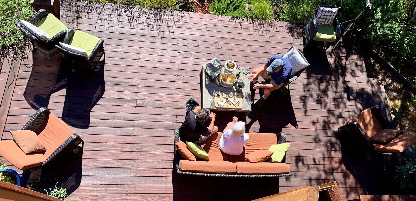 Top angle view of  small group enjoying an outdoor gathering with drinks on a wooden deck