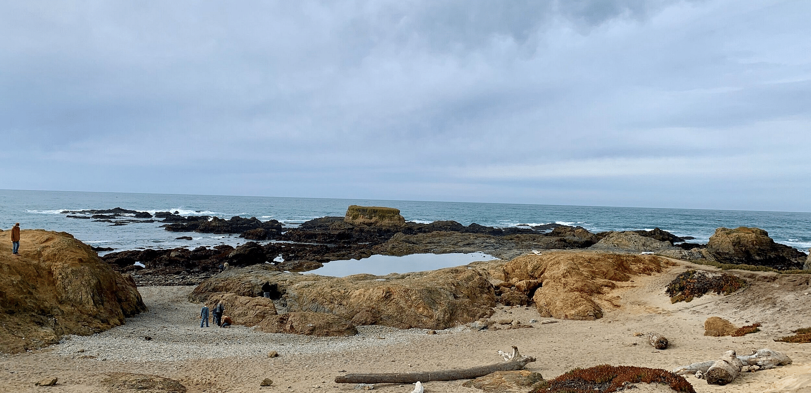 An image of a sea side featuring steep rocks where people are wandering