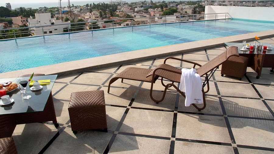 Lounging chair with a table by a pool at Hotel Atithi - TGI Grand, Pondicherry