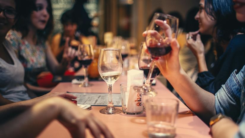 A group of people at a table raising their glasses in a toast, enjoying a social gathering.