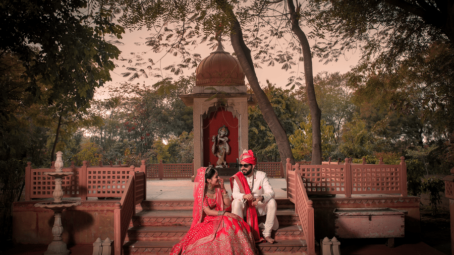 Bride and groom seated in a heritage courtyard during a traditional wedding photoshoot.
