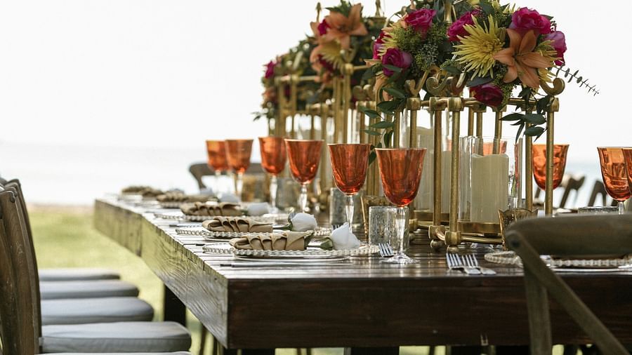 an image of a dining table with flower vases and and wine glasses.