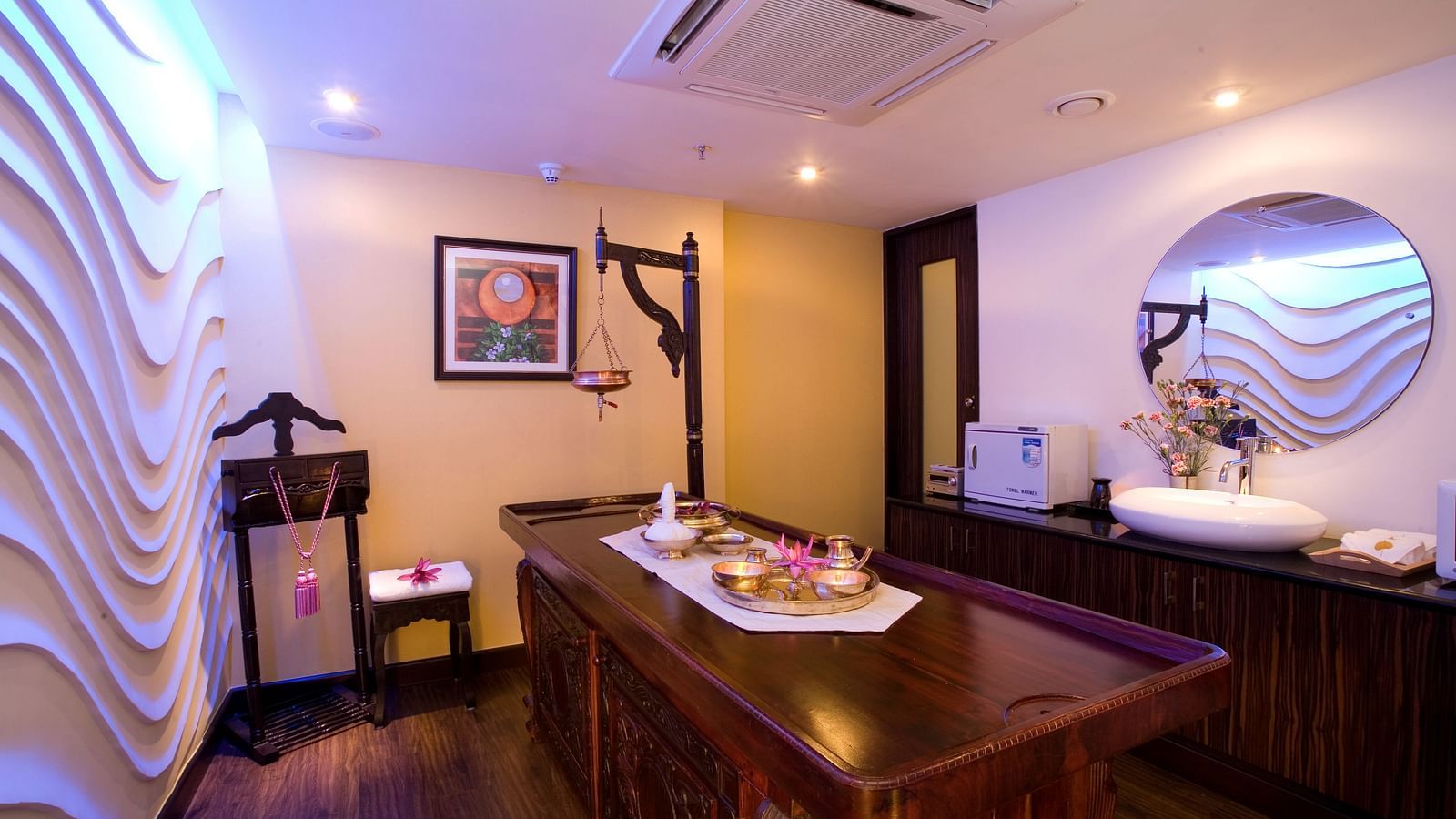 A side view of spa table in front of textured wall at Grand Chennai By GRT Hotels.