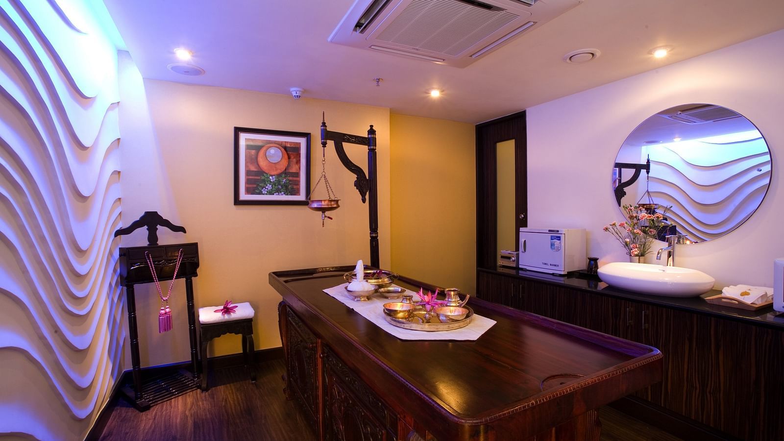 A side view  Spa table in front of textured wall at Grand Chennai By GRT Hotels.