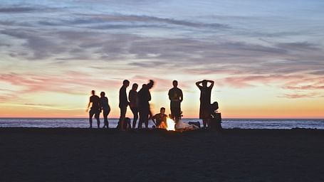 a group of people enjoying a bonfire by an ocean