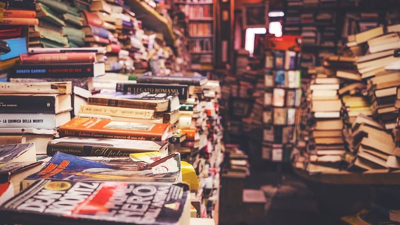 a close up shot of many books kept on top of each other at a second hand shop