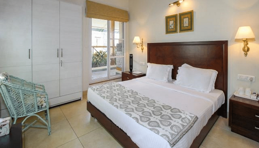 Closer view of deluxe room with tidy white linens and wardrobe on the side along with bedside lamps enhancing the beauty of the room - Lamrin Norwood Green, Palampur