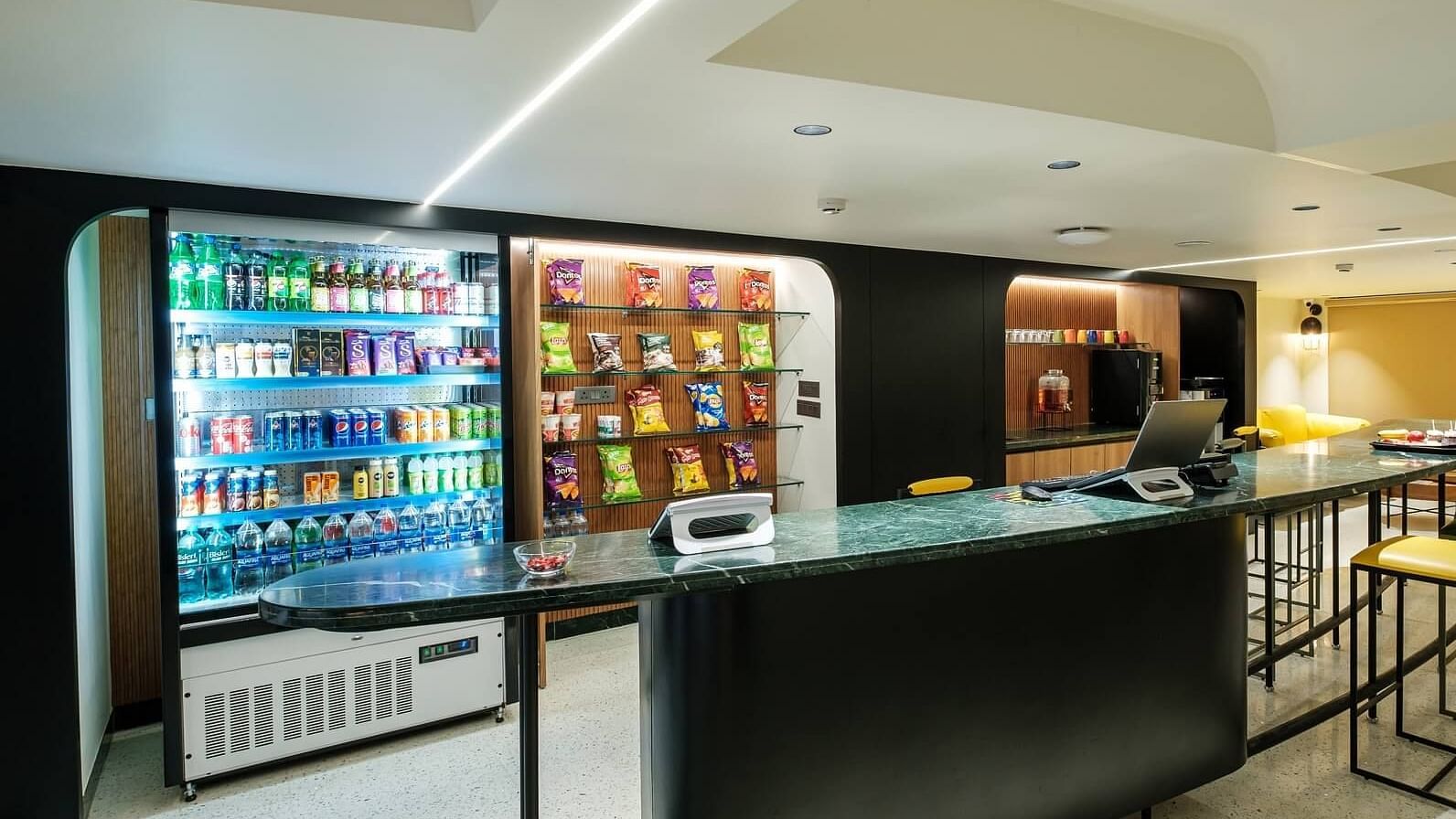 Vending machines at Indie Stays, Jaipur, stocked with snacks, alongside a large table and chairs placed in front for convenience.