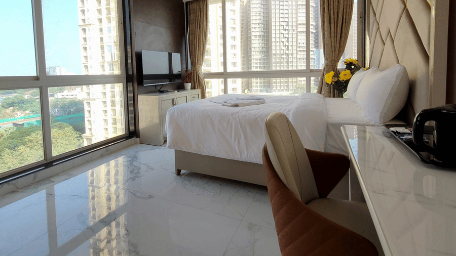 deluxe room at Maxxvalue Hotel, Chitranjan Tower, Powai with a posh bed and white linens along with floor-to-ceiling windows offering ciy view2