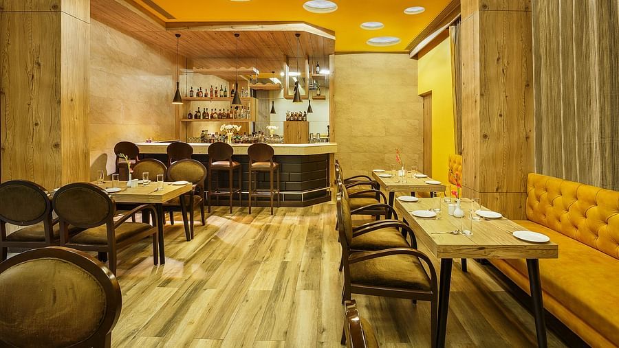A bar setting at The Manor in Bareilly, featuring wooden tables and shelves lined with various bottles