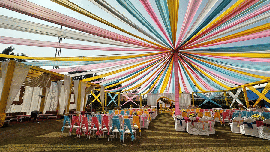 Colorful outdoor wedding setup under a vibrant canopy at Amer Greens, with arranged seating and festive decor.