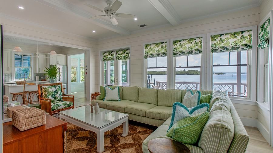 A broad, inviting living area furnished with multiple sofas, a central coffee table, a television, and numerous windows offering natural light - Abaco Inn