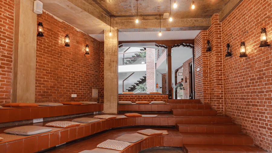 Modern terraced seating area with traditional red brick walls and elegant lighting inside a boutique Kathmandu building, Nepal.