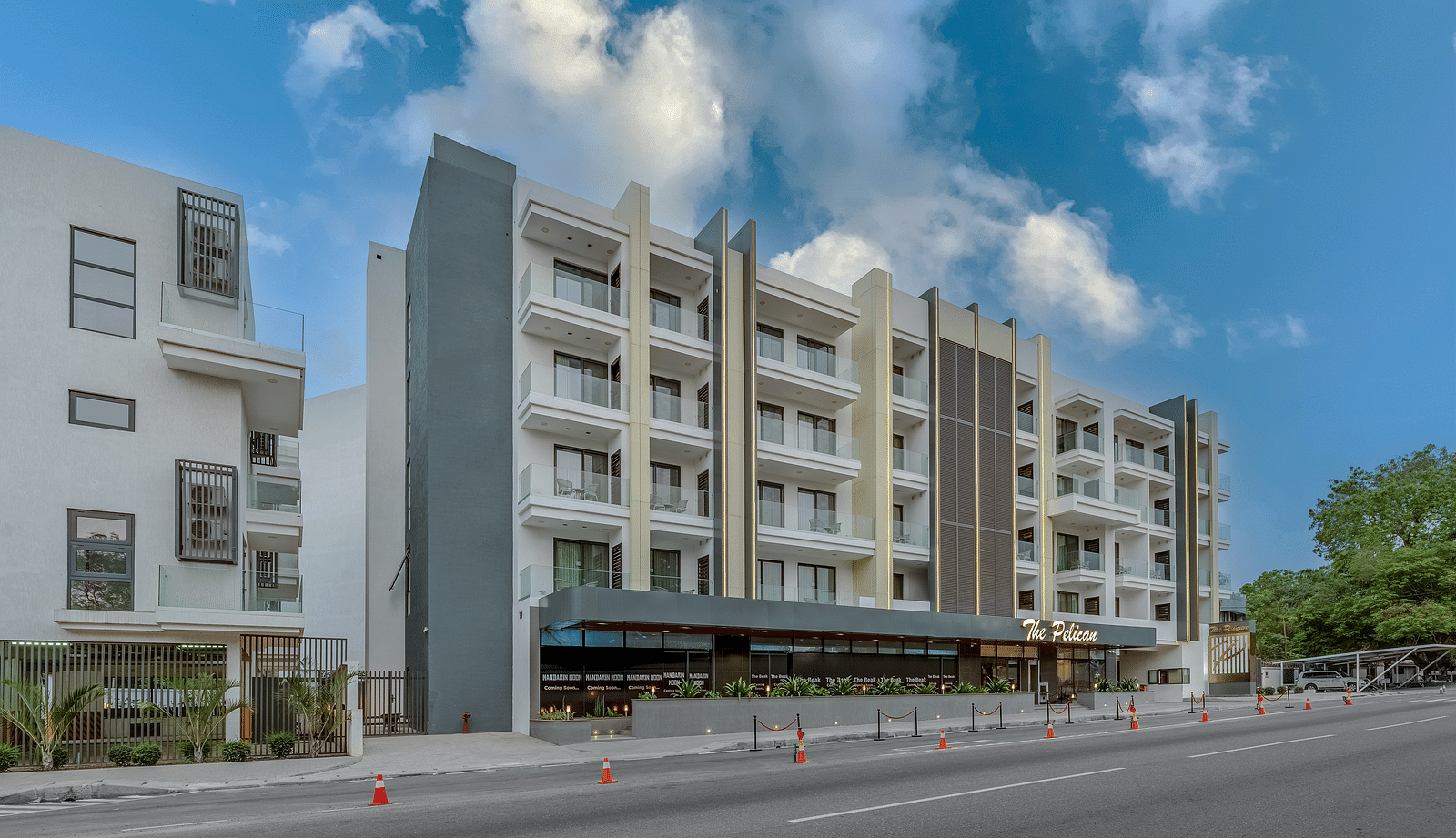 A multi-story hotel building with a covered walkway and a street in front. - The Pelican Hotel, Accra