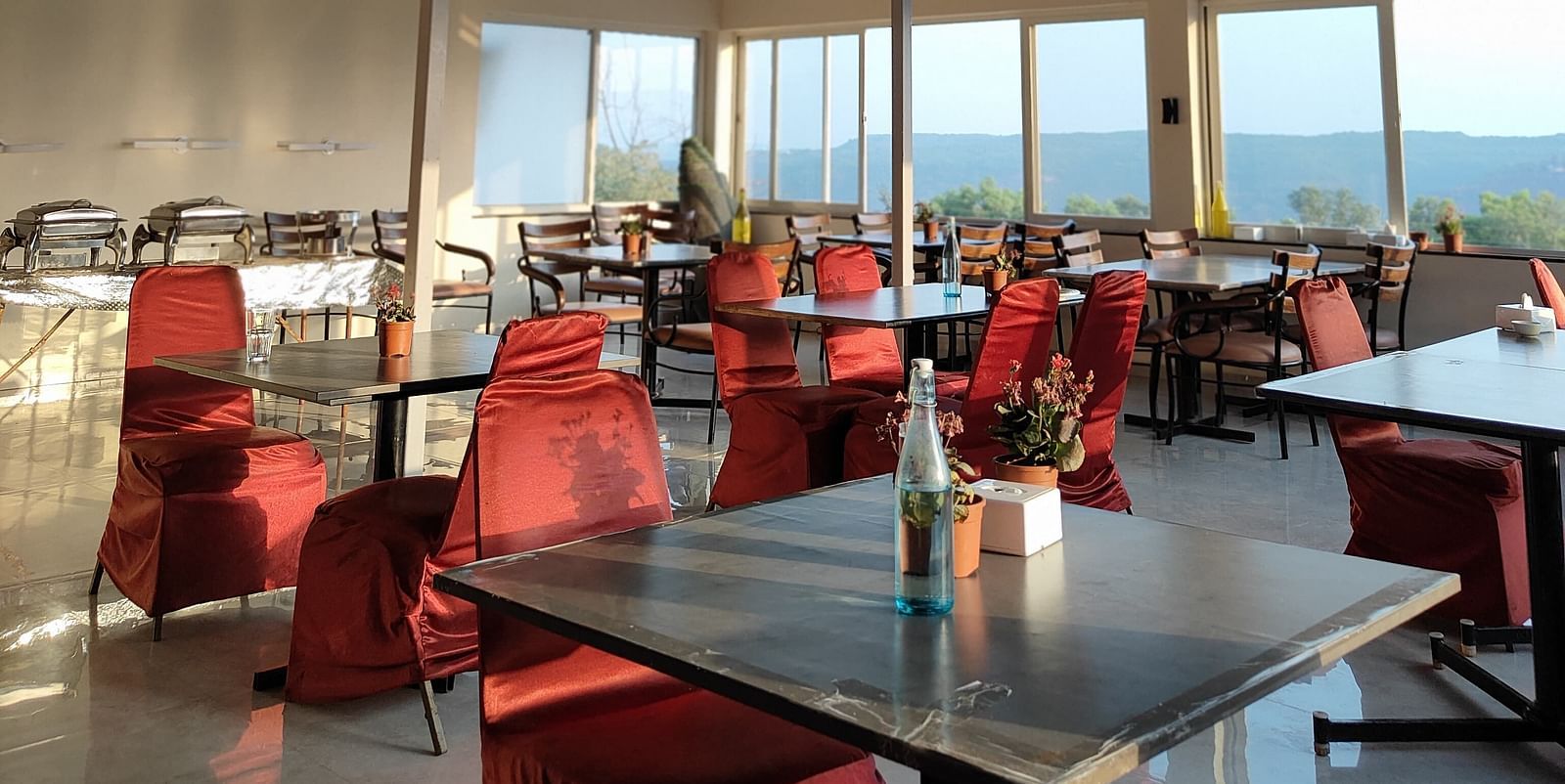 The interior of a dining area with metal beams and red chairs.