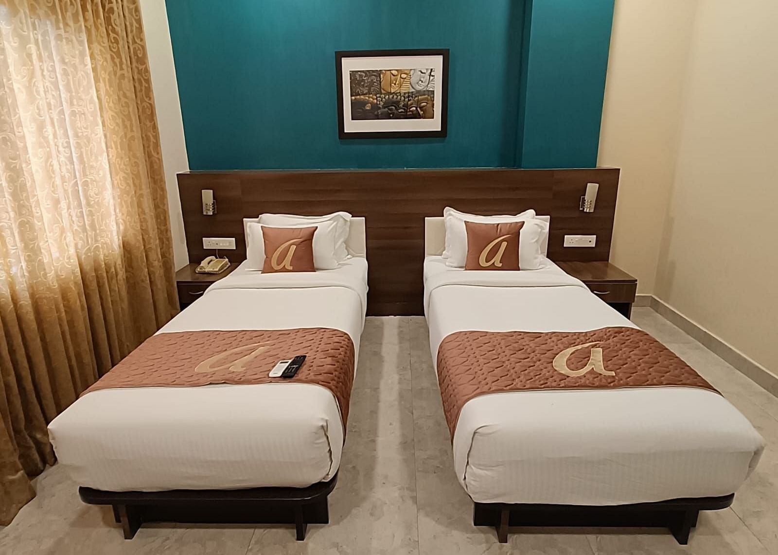View of Twin Deluxe Room at Astra Hotels and Suites, Whitefield where two beds are arranged side by side and a image hanging on the wall in the background.