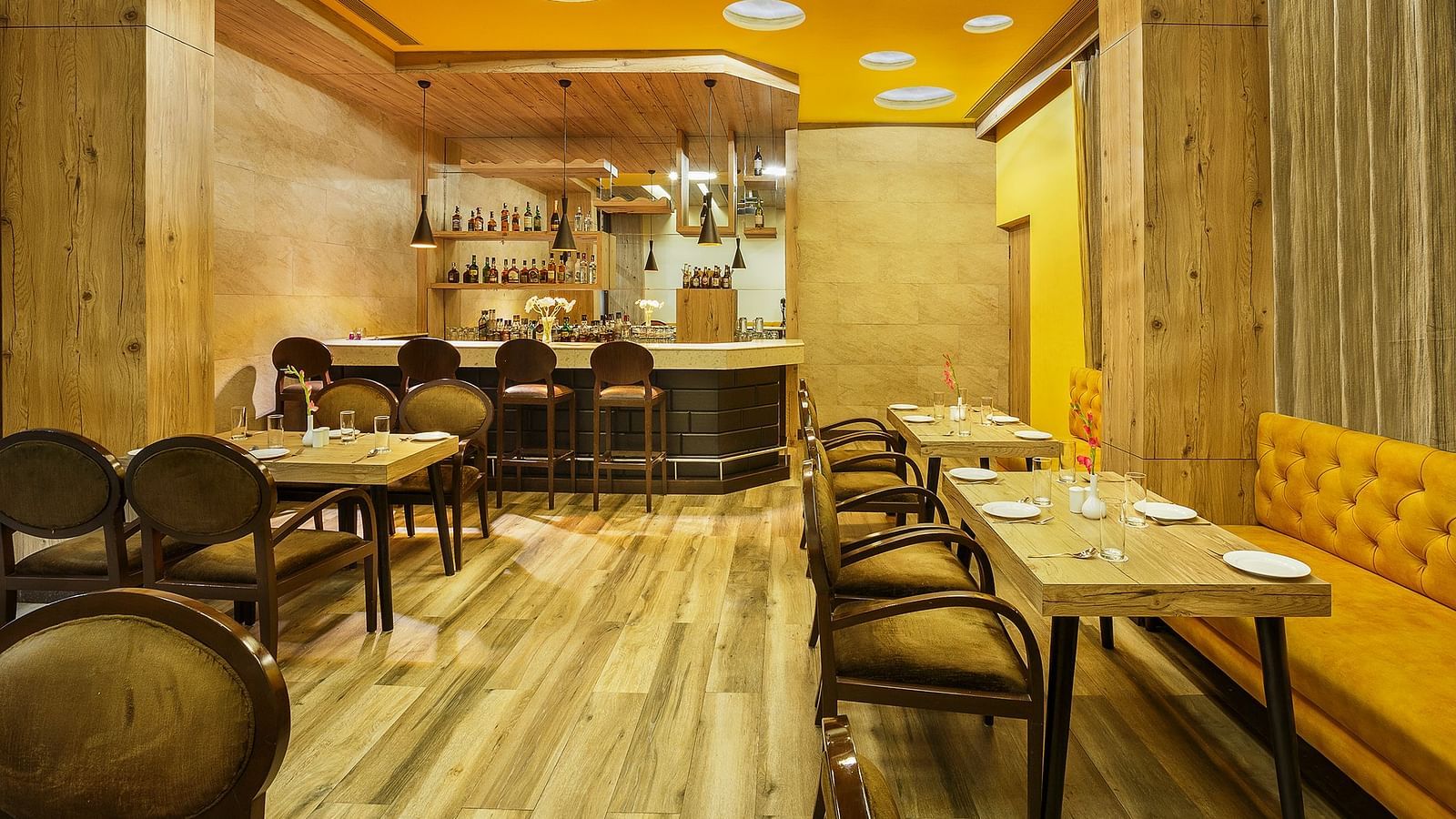 A bar setting at The Manor in Bareilly, featuring wooden tables and shelves lined with various bottles