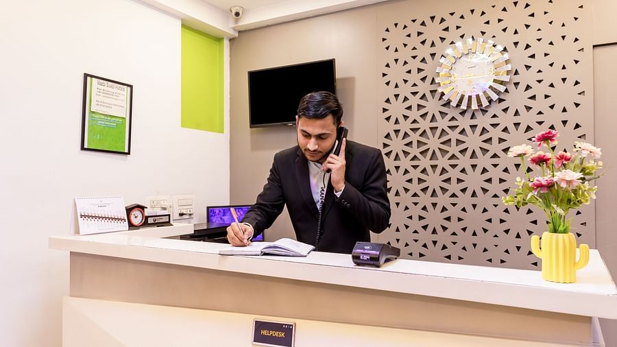 Hotel reception area with a professional staff member on a phone call at Hotel Bawa, Gurgaon.
