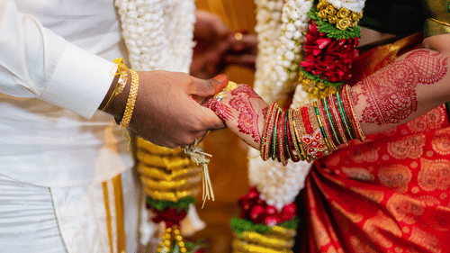 A man in traditional attire holding a hand of his fiancee who is also wearing a traditional attire in an engagement ceremony. 