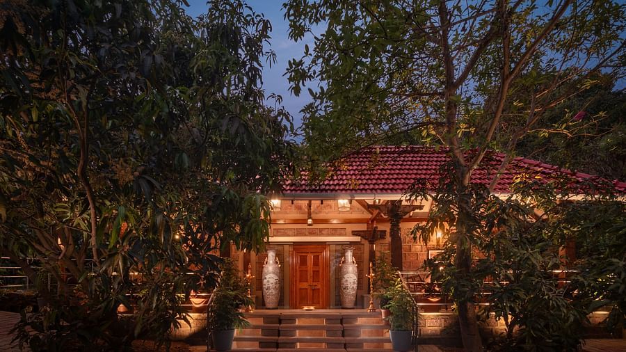 The night view of a building with terracotta rooftop and warm lighting surrounded by lush greenery - Highland Sarovar Portico, Sindhudurg