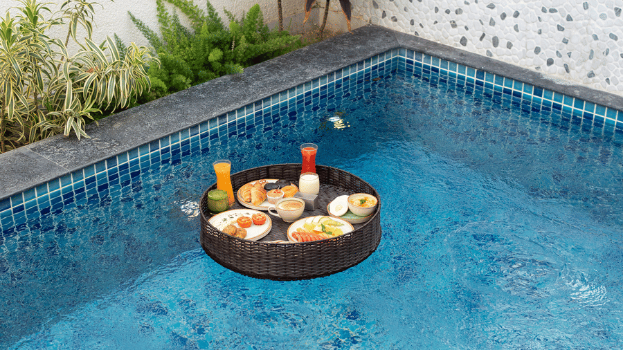 WaterHole Private Pool Villa Breakfast with a wooden floating tray holding breakfast items and drinks at The Golden Tusk, Jim Corbett