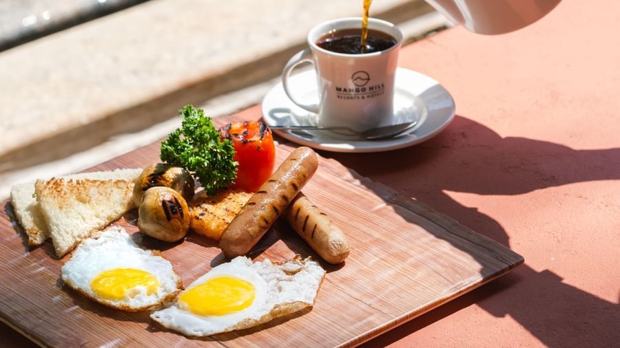 Poolside breakfast with eggs, sausages, bread, and coffee  | Mango Hill, Pondicherry
