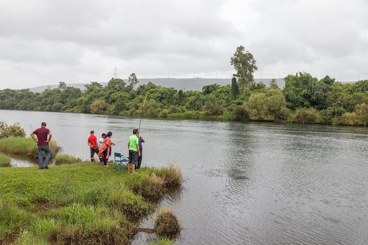Guests at Forest Escapes Koyna enjoy the view of a river or lake from the shore.