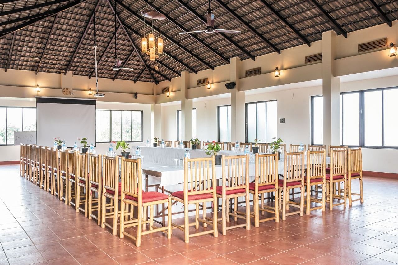 A long, elegantly set table in the event hall at Forest Escapes Koyna awaits guests.