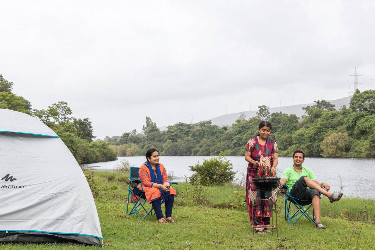 Camping at Forest Escapes Koyna with tents pitched near a scenic water body.