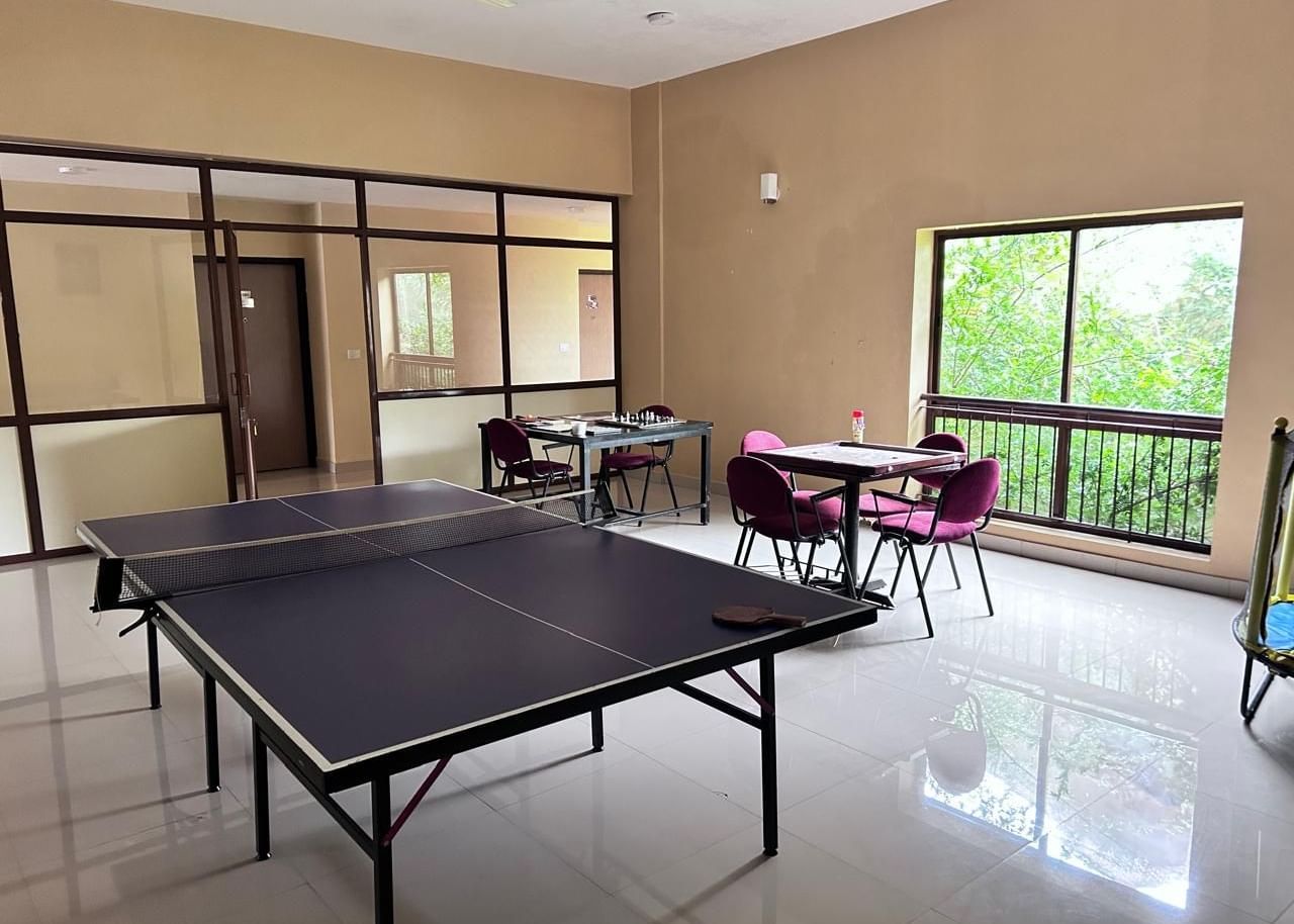 The recreational room at Paradise Wild Hills Resort, Kollur, with a table tennis table and a seating area.