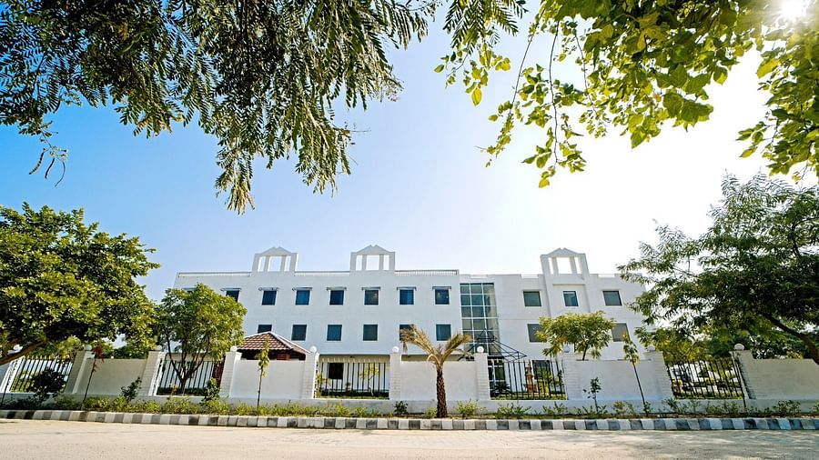 Front view of Grassfield Riveria Resort, Jaipur, surrounded by trees and clear skies, showcasing the modern building facade.