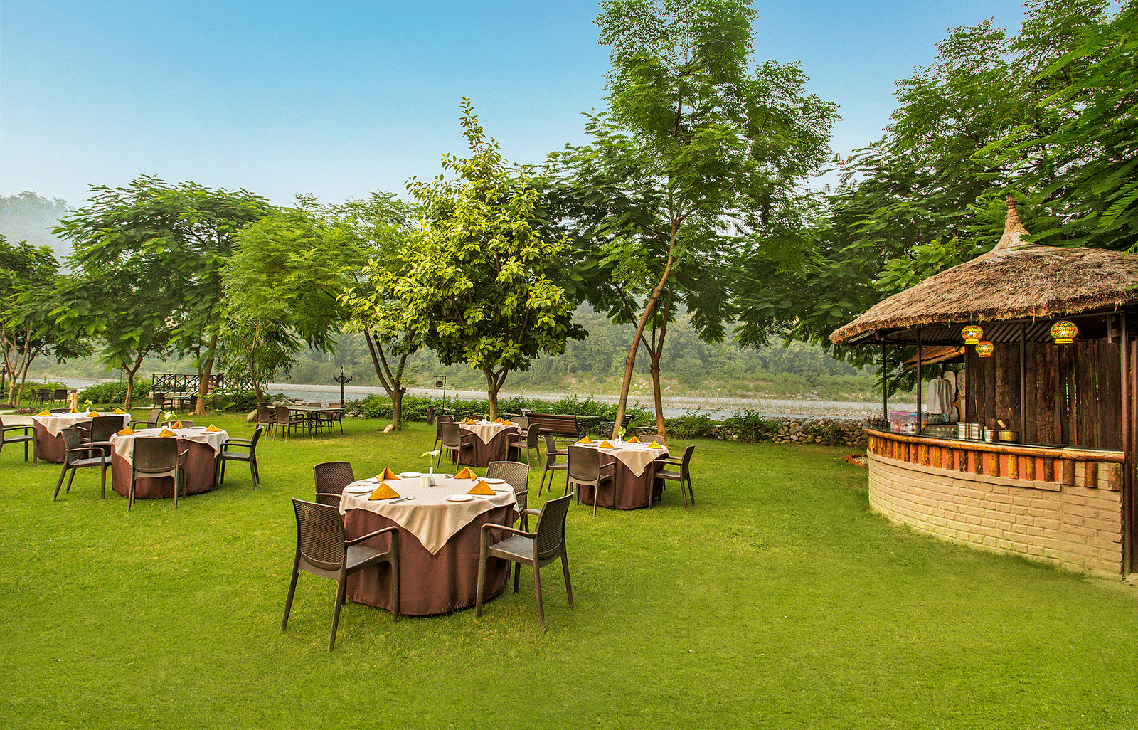An image of a seating arrangement in a lawn near a hut - The Riverview Retreat,  Corbett