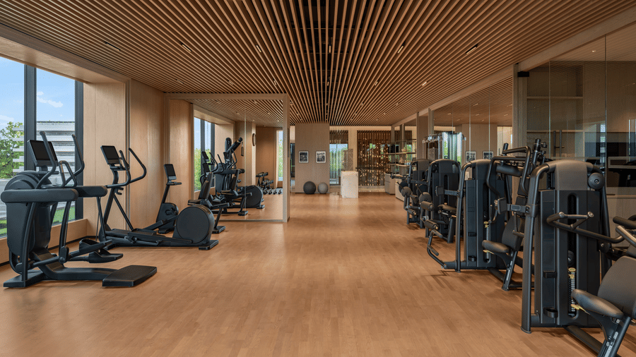 Gym with rows of cardio and strength training equipment on wooden flooring at The Residency Signature Madurai.