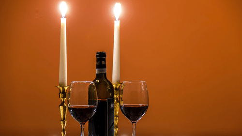 a bottle of wine, wine glasses and candles on a table