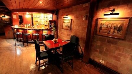 Bar with tall chairs and tables, featuring a dark-themed setup for guests to enjoy their drinks.