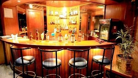 Bar with high chairs and tables, set in a dark theme for guests to savour their drinks.