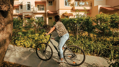 A girl riding a bicycle on a path surrounded by buildings at Karma Chalets.