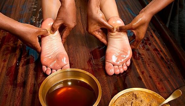 a person getting a foot massage with oil and ayurvedic paste at Ocean Spray Puducherry 