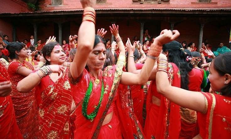 A group of women dancing wearing red saree