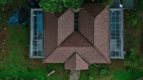 An aerial view of a building with a unique M-shaped roof, surrounded by lush greenery at Abad Brookside Lakkidi, Wayanad.