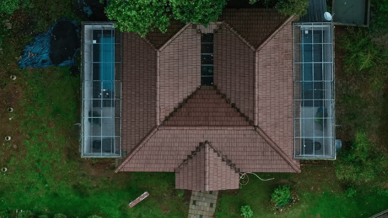 An aerial view of a cottage with a unique M-shaped roof, surrounded by lush greenery at Abad Brookside Lakkidi, Wayanad.