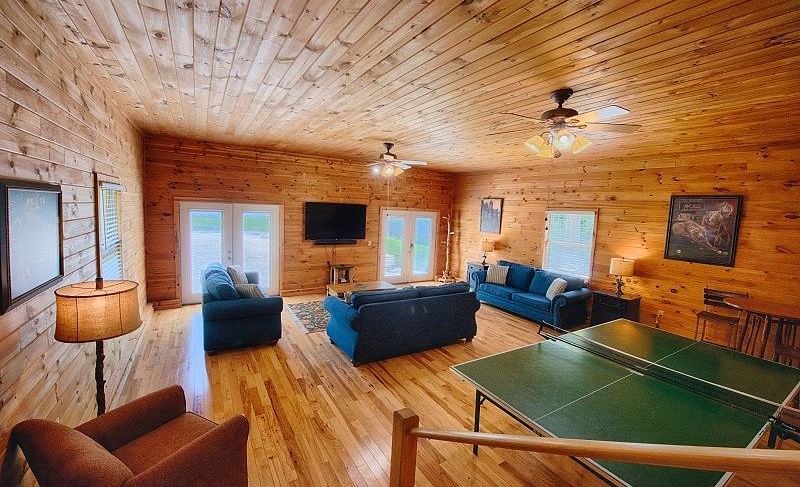 the living area of the river house with wooden interiors featuring a ping pong table and a seating area with blue couch set - Historic Tapoco Lodge