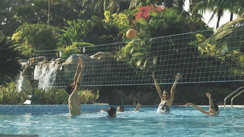 A group of people playing volleyball in a swimming pool at The Retreat Hotel & Convention Centre.