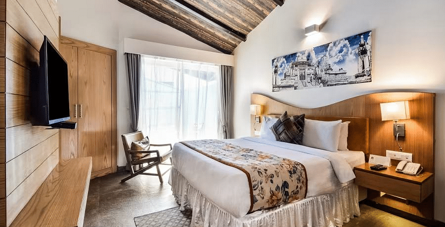 A modern hotel room with a plush bed, a TV, and a wooden accent wall. - Bamboo Saa Resort & Spa, Udaipur