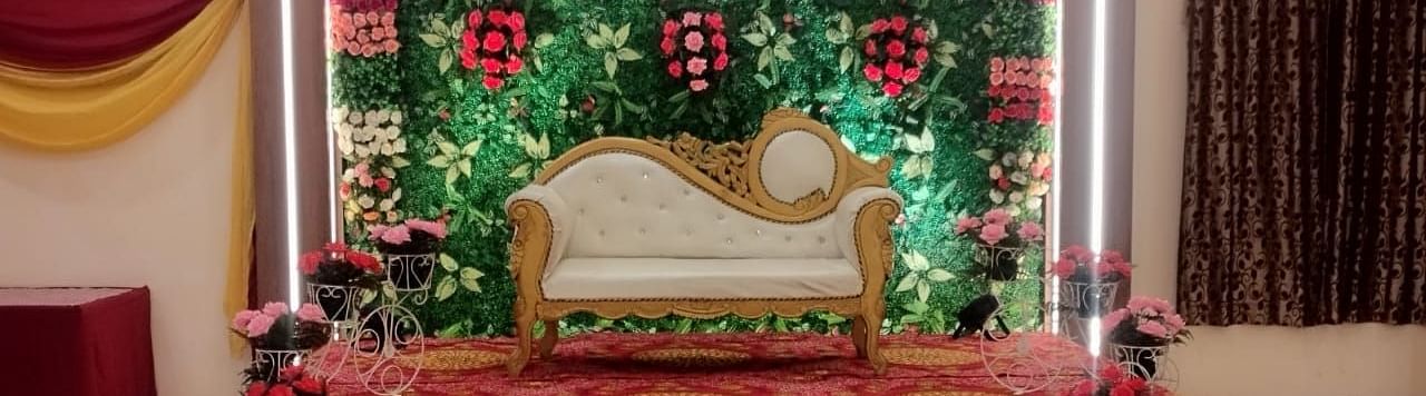 An event hall in Roorkee, elegantly arranged with a chair for the bride and groom adorned with flowers on the walls - Motel Divine International, Roorkee