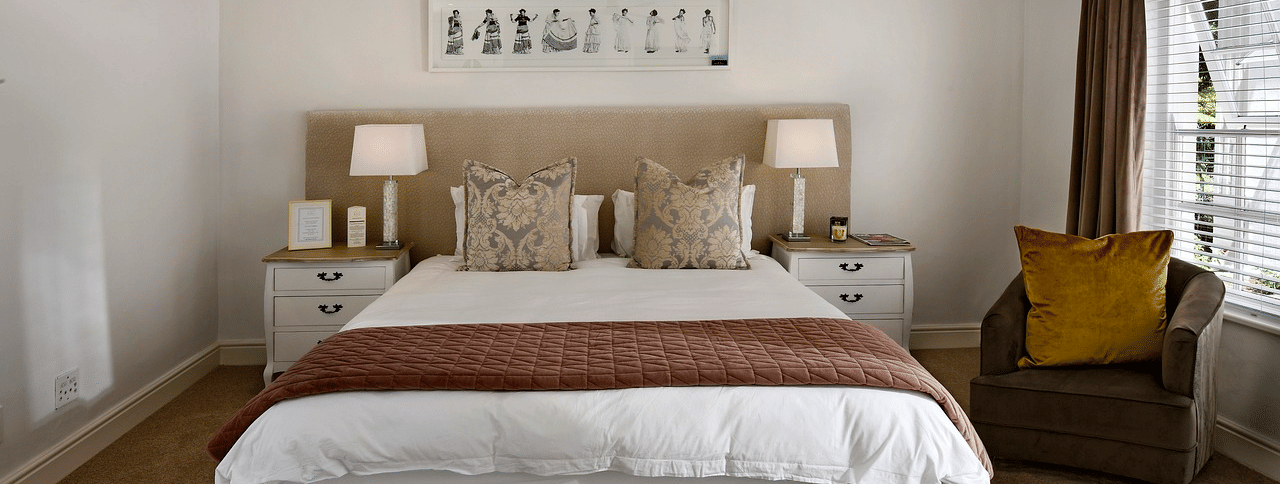A double bed with a ceiling fan hanging over it in a bedroom.