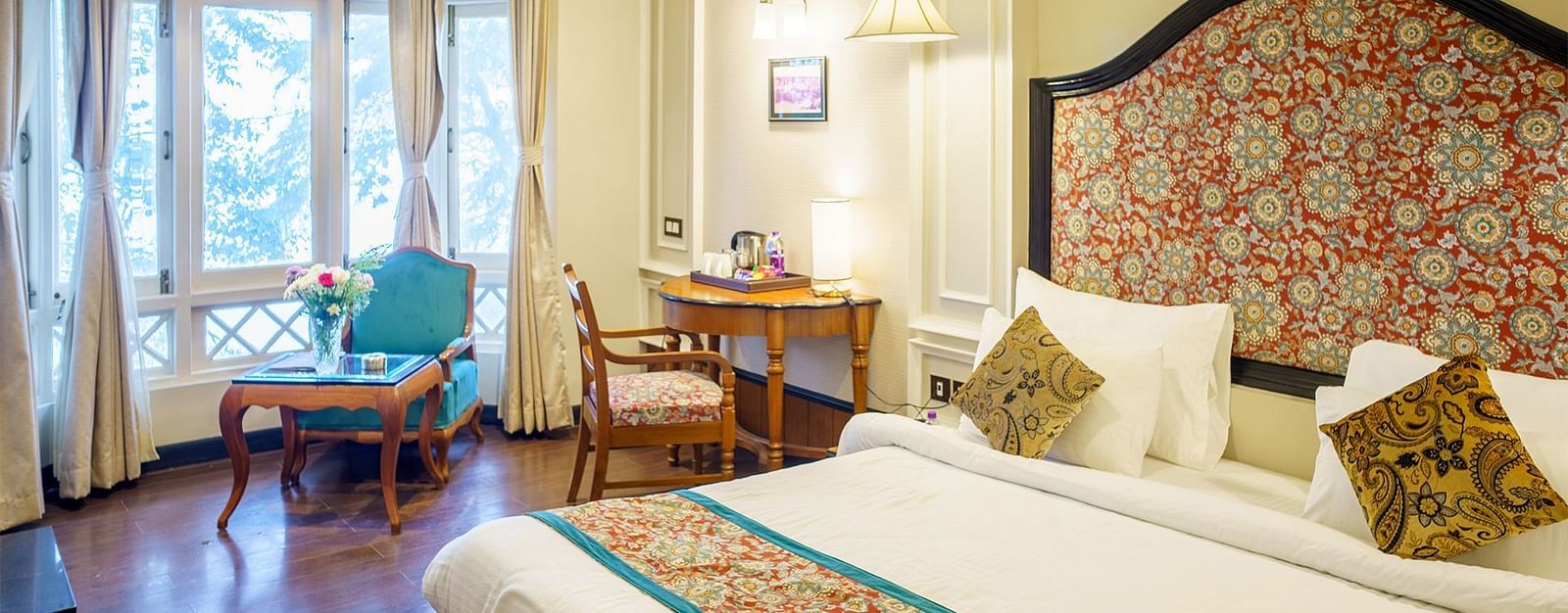 A room at Orsino Spa Resort with a large bed, a decorative headboard, and a small sitting area near a window.